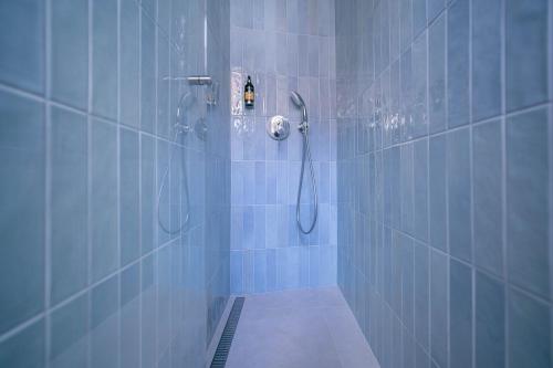a bathroom with a shower with blue tiles at Penzion Havran in Litomyšl