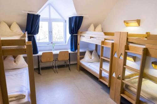 Zimmer mit Etagenbetten, einem Tisch und einem Fenster in der Unterkunft Jugendherberge Husum in Husum