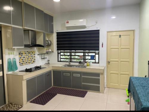 uma cozinha com armários cinzentos, um lavatório e uma janela em NO 5 NAZIRIN HOMESTAY Tmn Desa Manjung em Lumut