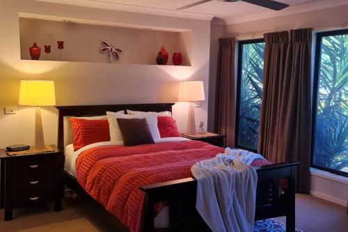 a bedroom with a bed with red sheets and windows at Sojourn on Stewart - Mansfield House with Spa Bath in Mansfield