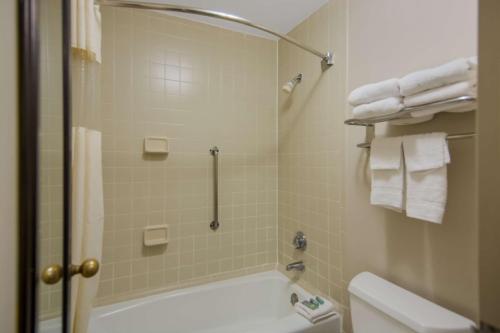 a bathroom with a tub and a toilet and towels at Best Western Aquia Quantico in Stafford