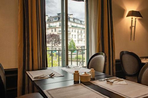 een eetkamer met een tafel en een groot raam bij Best Western Plus Le Moderne in Caen
