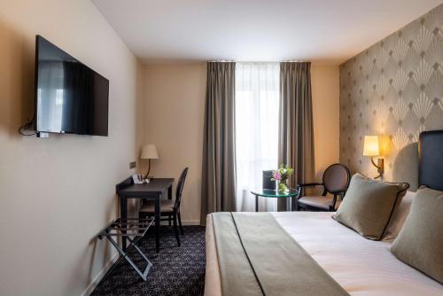 a hotel room with a bed and a desk at Best Western Plus Le Moderne in Caen