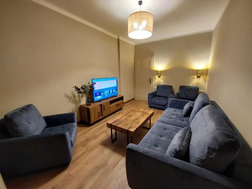 uma sala de estar com dois sofás azuis e uma televisão em Two bedrooms, close to the center, fully equipped! em Cracóvia