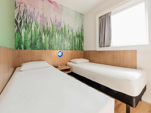 2 Betten in einem Zimmer mit Wandgemälde in der Unterkunft ibis Styles Araraquara in Araraquara