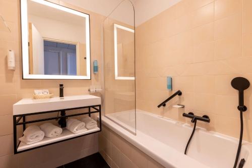 y baño con lavabo, bañera y espejo. en Best Western Hotel Matisse en Sainte-Maxime