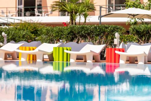 a pool with colorful chairs and an umbrella at Hotel San Michele in Celle Ligure