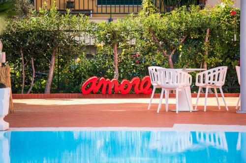 two white chairs and a table next to a pool at Hotel San Michele in Celle Ligure