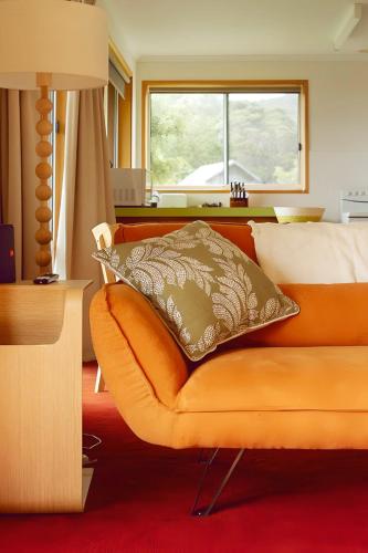 a bedroom with an orange couch and a window at Little Belmont in Lunawanna