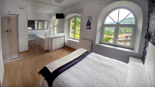 um quarto com uma cama grande e 2 janelas em Alojamiento rural El Refugio em Tudanca