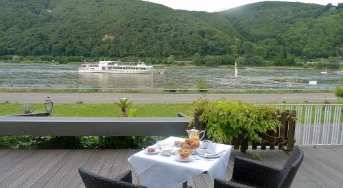 a table on a balcony with a boat in the water at Hotel Schön in Aßmannshausen
