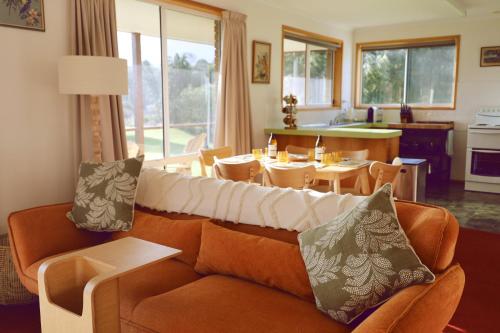 Little Belmont في Lunawanna: غرفة معيشة مع أريكة وغرفة طعام