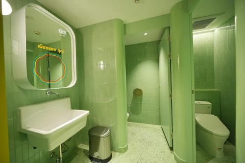 a green bathroom with a sink and a toilet at GO Hotel Si Racha at Central Si Racha in Si Racha