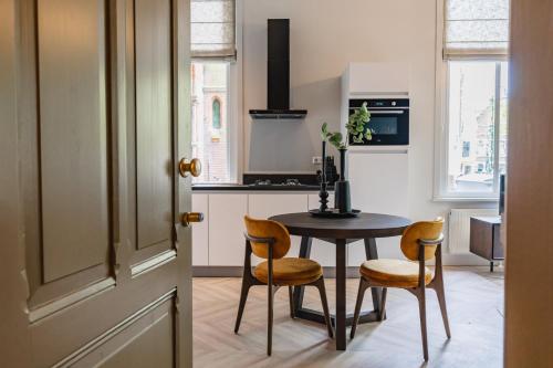 een keuken met een tafel en twee stoelen en een deur bij Shortstay - De Pastorie, Gouda in Gouda