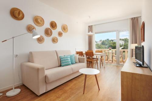 ein Wohnzimmer mit einem Sofa und einem Tisch in der Unterkunft Hotel Apartamentos Cala Santanyi in Cala Santanyi