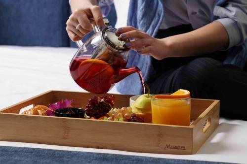 a person pouring a drink into a tray of fruit at Best Western Plus Congress Hotel Yerevan in Yerevan