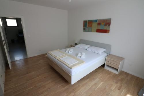 a bedroom with a white bed and a wooden floor at Apartment Sandrita in Kotor