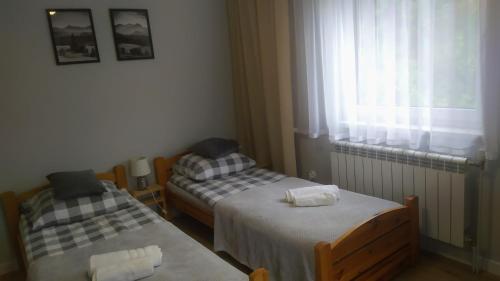 2 Betten in einem kleinen Zimmer mit Fenster in der Unterkunft Pod Wdżarem in Kluszkowce