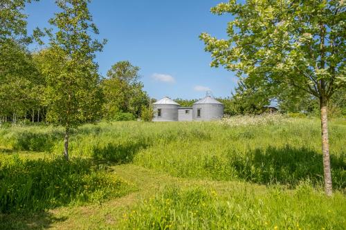 a field with two domed buildings in the distance at Extraordinarily converted grain stores - The Silos in Ipswich