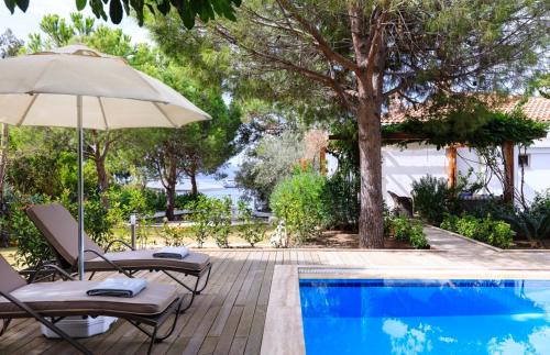 uma piscina com duas cadeiras e um guarda-sol ao lado em Villa Ruyam em Marmaris