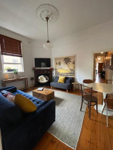 a living room with a blue couch and a table at Iconic Lygon street Home, Carlton in Melbourne
