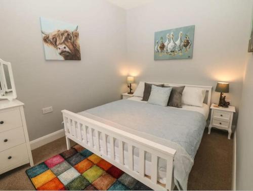 - une chambre dotée d'un lit blanc avec une photo de vache sur le mur dans l'établissement Sunshine Cottage Tideswell, Games room included., à Tideswell