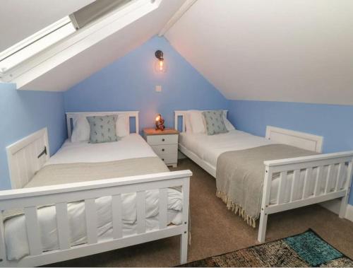 two beds in a attic bedroom with blue walls at Sunshine Cottage Tideswell, Games room included. in Tideswell