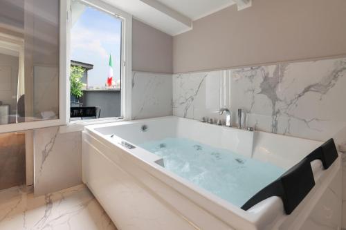 a large tub in a bathroom with a window at PRESTIGE BOUTIQUE APARTHOTEL - Piazza Duomo View in Milan