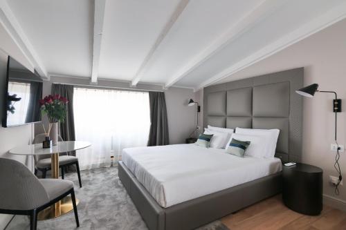 a bedroom with a large white bed and a table at PRESTIGE BOUTIQUE APARTHOTEL - Piazza Duomo View in Milan