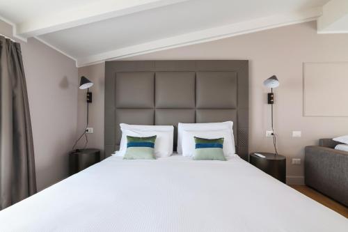 a bedroom with a large white bed with blue pillows at PRESTIGE BOUTIQUE APARTHOTEL - Piazza Duomo View in Milan