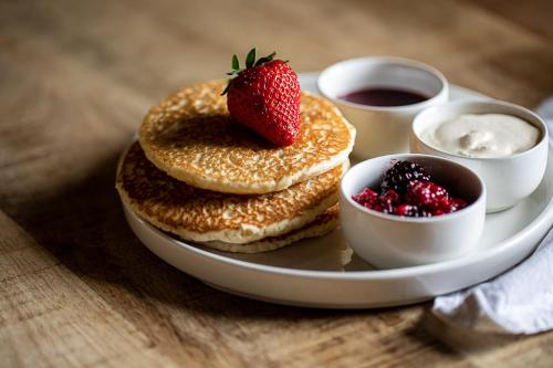 a plate with pancakes and a strawberry on a table at The Three Tuns in Helston