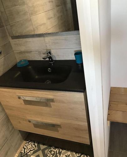 une salle de bain avec un lavabo noir et un miroir dans l'établissement Ker-Lina sea view, calm guaranteed, à Plounévez-Lochrist