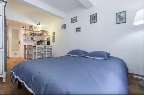 a bedroom with a blue bed and a kitchen at Le Fersen - cosy studio- coeur vieil Antibes in Antibes