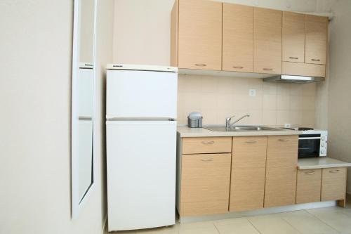 シビリにあるSiviri Roomsの白い冷蔵庫付きのキッチン(木製キャビネット付)