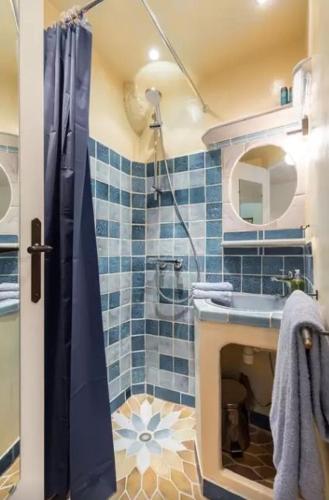 La salle de bains est pourvue de carrelage bleu, d'une douche et d'un lavabo. dans l'établissement Le Fersen - cosy studio- coeur vieil Antibes, à Antibes