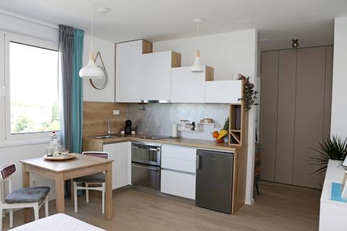 a kitchen with white cabinets and a small table at Studio CAMINO with parking in Zadar
