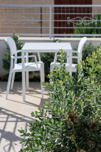 two white chairs and a table and a bush at Butiko in Castelluzzo