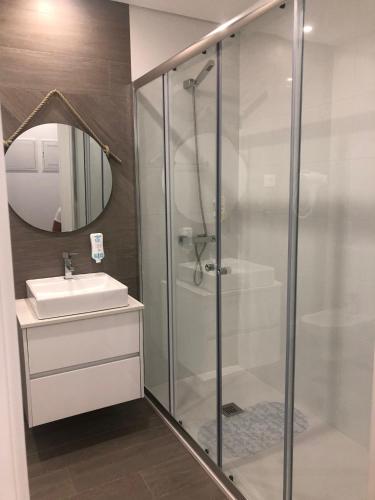 a bathroom with a glass shower and a sink at Apartamento Estrela do Mar in Nazaré