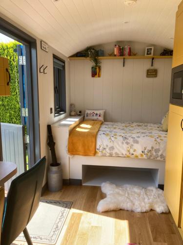 a small bedroom with a bed and a table at Atlantic Way Shepherd Hut in Moville