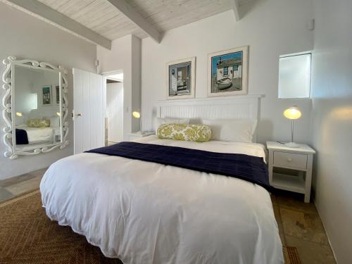 1 dormitorio blanco con 1 cama grande y espejo en Beach House en Paternoster