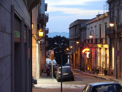 Una calle de la ciudad por la noche con coches aparcados en la calle en Al Teatro en Reggio Calabria