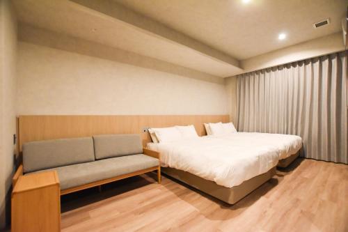 a small room with a bed and a couch at Randor Hotel Hiroshima Prestige in Hiroshima