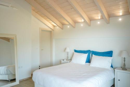 a bedroom with a large white bed with blue pillows at Liberte Maisonettes in Parga