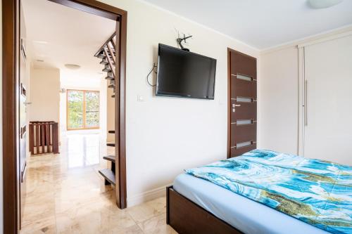 a bedroom with a bed and a tv on the wall at Apartament Ukiel z widokiem na jezioro in Olsztyn