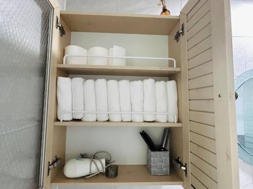 a cupboard filled with white towels in a bathroom at Areumdaumga Pension in Seogwipo