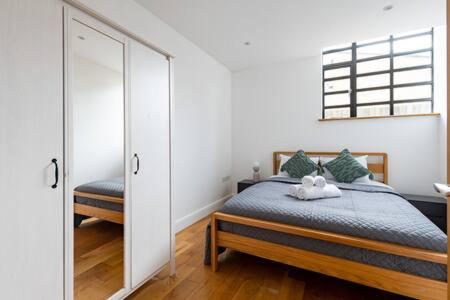 ein Schlafzimmer mit einem Bett und einem großen Spiegel in der Unterkunft Trendy East London Flat SH11 in London