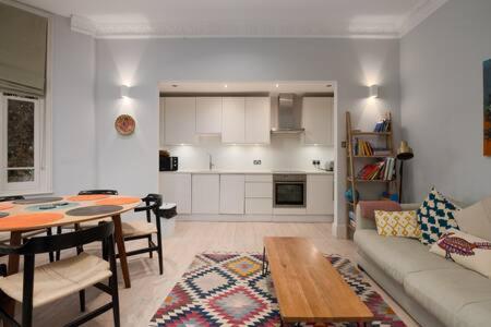 een woonkamer met een bank en een tafel en een keuken bij Trendy Hampstead Flat RH7 in Londen