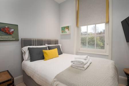ein weißes Bett in einem Zimmer mit Fenster in der Unterkunft Trendy Hampstead Flat RH7 in London