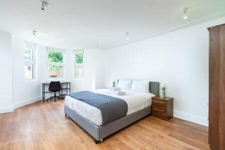 a large white bedroom with a bed and a desk at London Flat with Garden WPRA in London