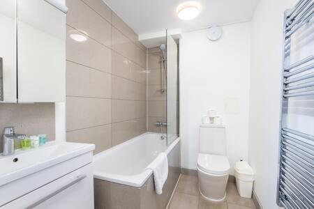 a white bathroom with a tub and a toilet and a sink at London Flat with Garden WPRA in London